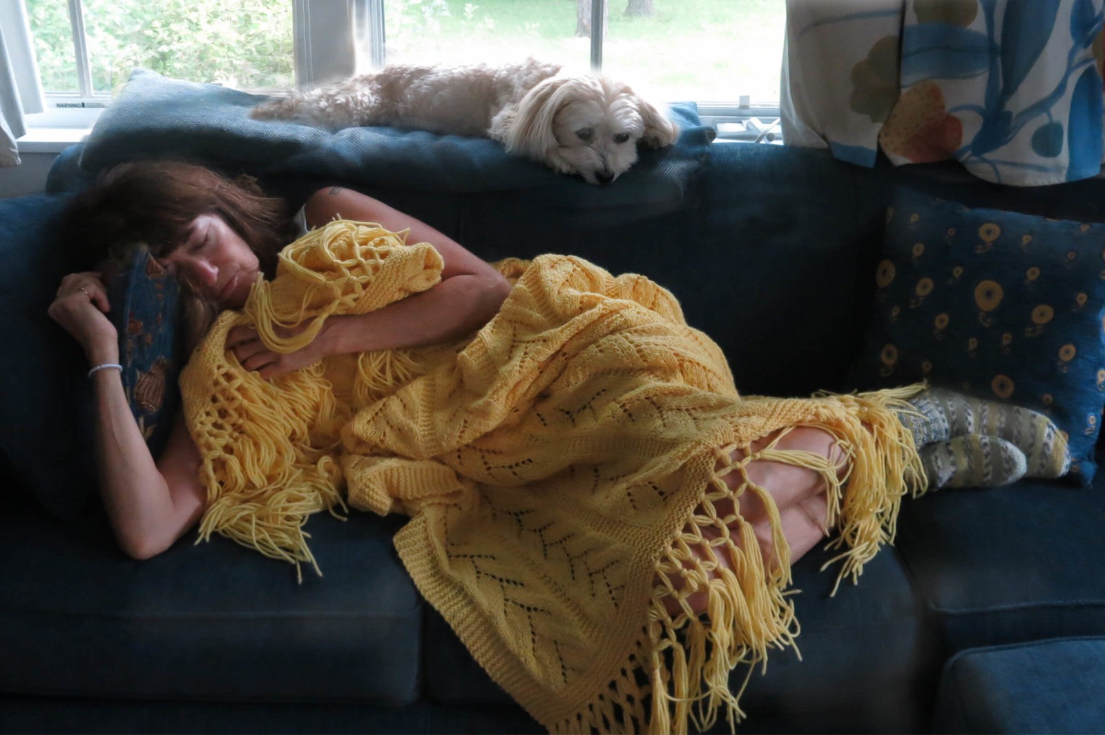 Sick with a cold, Robin Botie of Ithaca, New York, cuddles up with handknit afghan and dog.