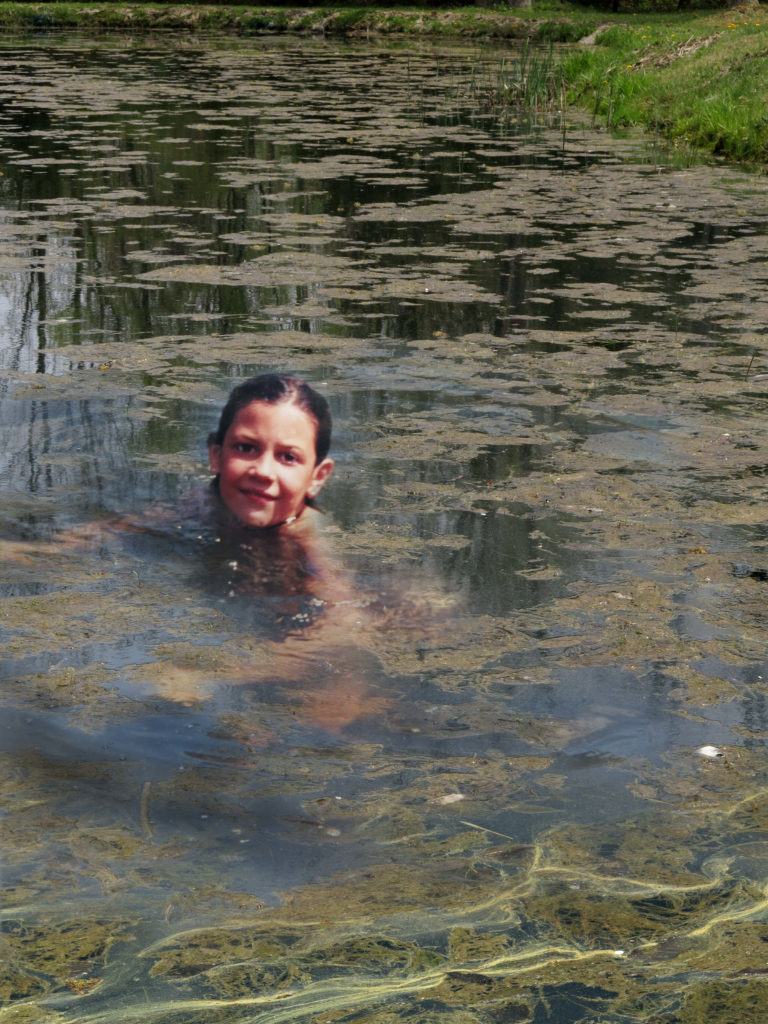 Staying Afloat -- Robin Botie in Ithaca, New York Photoshops daughter, Marika Warden, swimming in pond filled with algae.