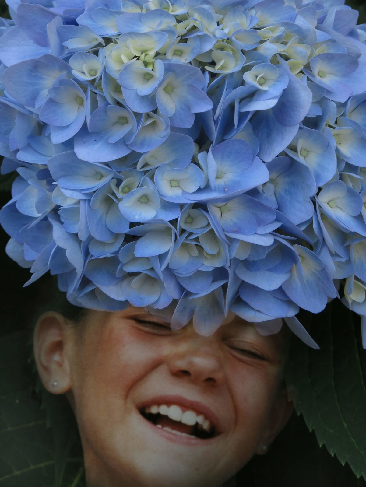 Robin Botie of Ithaca, New York, photographs a rhododendron and then Photoshops it over the face of her laughing daughter.