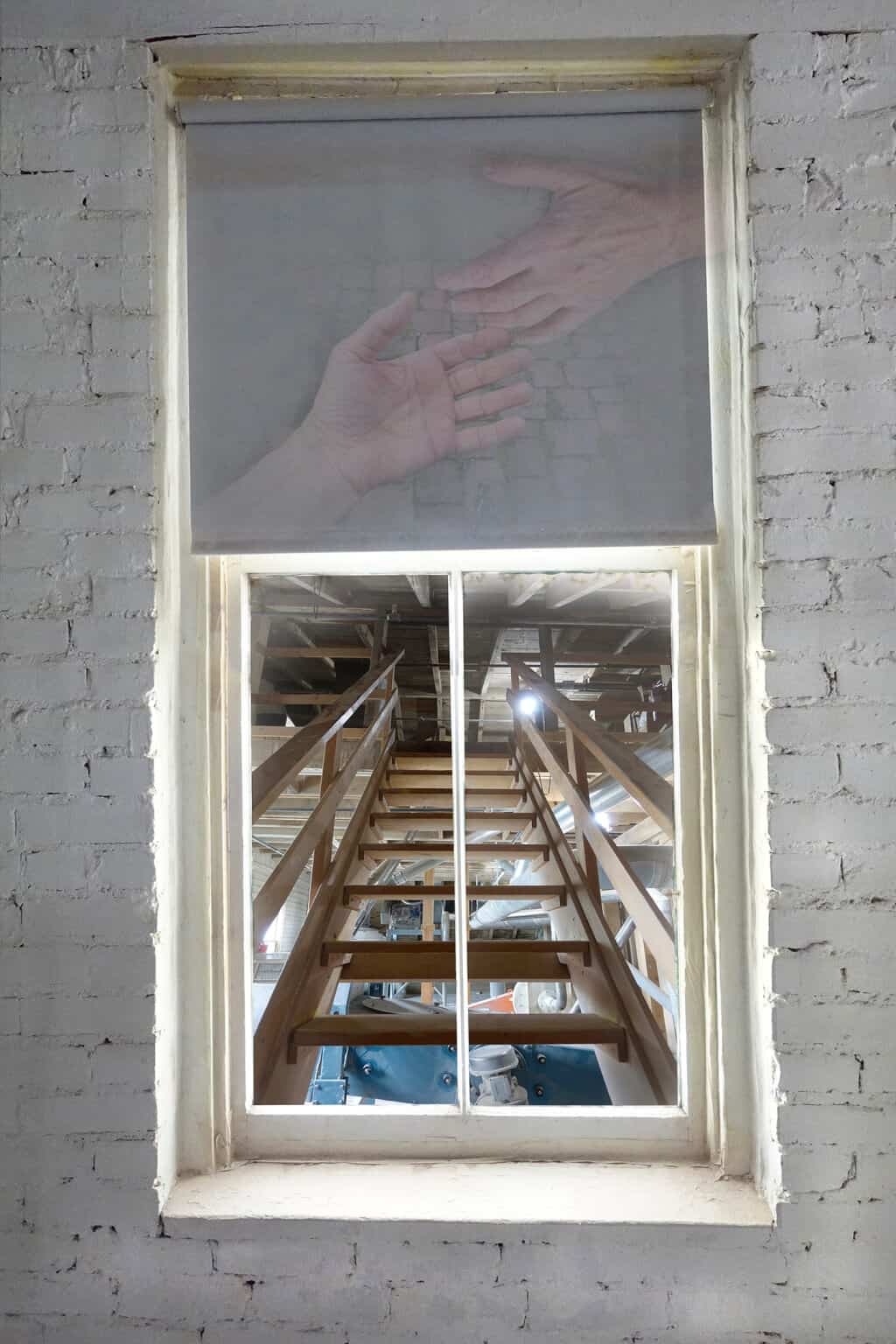 Robin Botie of Ithaca, New York, photoshops hands reaching out over a scene of brick wall and staircase.